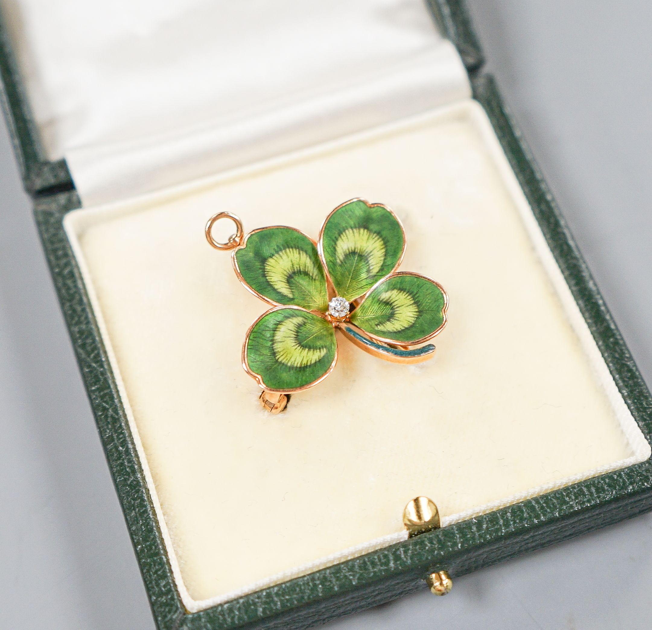 A yellow metal, two colour enamel and single stone diamond set clover pendant brooch, width 27mm, gross weight 6.6 grams.